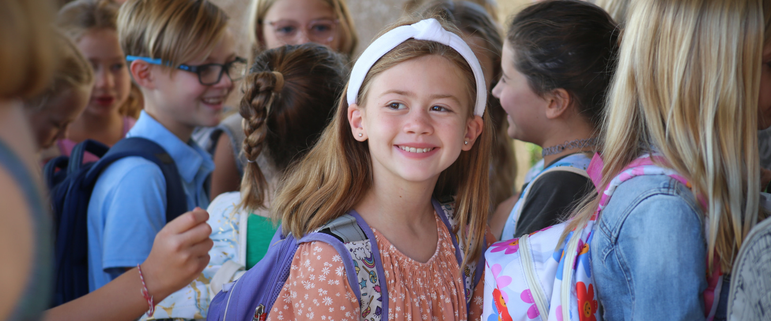 Image of a student with a backpack on walking through a crowd of other students